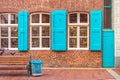 Facade of German house. Windows with blue shutters. Blue door. Blue trash can. Wooden bench. Royalty Free Stock Photo