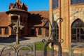 Facade of a gothic mansion. Gothic style architecture built of red bricks. Beautiful estate with tiled roof behind the fence