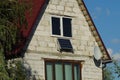 Facade of a gray brick house with windows with blue solar panels