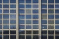 Facade of high glass modern building with square windows and a reflection of blue sky Royalty Free Stock Photo