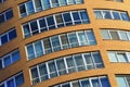 Facade of a high modern multi-storey building, a skyscraper. Background of a yellow residential tower, large glass Royalty Free Stock Photo