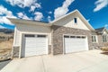 Facade of home with gable roof white garage doors and stone wall against sky Royalty Free Stock Photo