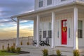 Facade of home with red door porch stairs and yard