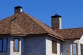 Part of the house of gray brick with windows under a brown tiled roof against the blue sky Royalty Free Stock Photo