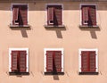 Facade of a house in the Mediterranean style, plaster painted in sand color with closed wooden shutters in dark red, partially Royalty Free Stock Photo