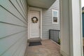 Facade of house with porch and white wooden front door decorated with wreath