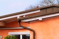 Facade of a house with a roof, a plastered wall, a drain pipe against a blue sky Royalty Free Stock Photo