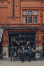 Facade of HR Higgins coffee shop in Mayfair, London, UK, people in face masks queue outside