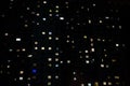 Facade of a large multi-storey block of flats with many lighting windows in apartments night view