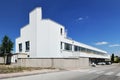 Facade of a lonely industrial building with white cladding, many windows and a clear blue sky