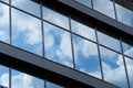 Facade of a modern building on a bright Sunny day, blue sky and clouds reflecting in a glass, beautiful exterior of the new Royalty Free Stock Photo