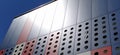 Facade of a modern building. Red, blue and white slabs or metal profiles with decorative holes Royalty Free Stock Photo
