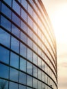 Facade of modern glass building and round shape at sunset, Clouds reflection in a windows. Warm and cool tone contrast. Sun flare Royalty Free Stock Photo