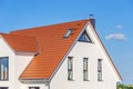 Facade of a modern house with red tiled roof, blue sky