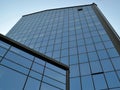 Facade of a modern office building made of glass and concrete with mirror windows against the blue summer sky on a summer day Royalty Free Stock Photo