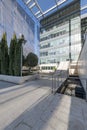 Facade of an office building with glass and metal, granite surfaces with marble stairs with metal railings and decorative trees Royalty Free Stock Photo