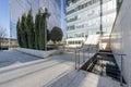 Facade of an office building with marble stairs with metal railings and decorative trees