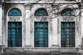 Facade of old abandoned building with three large arched windows of blue glass and columns. Monochrome background Royalty Free Stock Photo