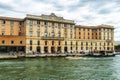 Facade of old beautiful building with clock, balcony and flags of Venice, Italy and European Union on the shore of Grand Canal in Royalty Free Stock Photo