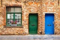 The facade of an old brick house with a window and two wooden doors Royalty Free Stock Photo