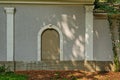 Facade of an old building with a closed window with an arch and columns on a sunny day Royalty Free Stock Photo