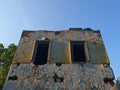 The facade of an old building that is collapsing against the blue sky. Broken windows of an old house Royalty Free Stock Photo