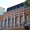 The facade of old building is decorated with a statue of a woman and half-columns Royalty Free Stock Photo