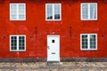 Facade of an old building with a window and an entrance door against a red brick. Royalty Free Stock Photo