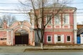 The facade of an old building with a wooden porch and an arched gate to the courtyard