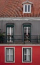 Facade of old colorful house with orange tiled roofs in Lisbon, Portugal. View on red building with balcony and windows Royalty Free Stock Photo