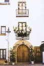 Facade of old European house with windows, balcony with flowers, wooden door in the shape of an arch Royalty Free Stock Photo