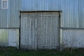 Facade of an old garage with a metal wall and gray closed wooden gates