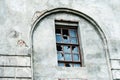 The facade of an old house with broken windows. Gray wall with decorative arch and wooden window frame. Flat lay frame Royalty Free Stock Photo