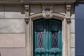 Facade of old house with classical architecture sculptural arch doorway and green painted wooden door with rhombus pattern grids