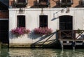 Facade of old house with pink flowers on windows, on a canal in Venice, Italy Royalty Free Stock Photo