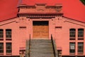 the facade of an old industrial building or warehouse, brick walls painted red, red roof, wooden door for the entrance to the Royalty Free Stock Photo