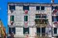 Facade of an old palazzo in Venice with the venetian flag in every window.