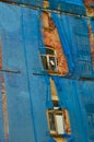 The facade of an old ruinous building is mantled with some blue curtains to protect the pedestrians