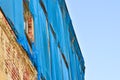 The facade of an old ruinous building is mantled with some blue curtains to protect the pedestrians