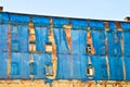 The facade of an old ruinous building is mantled with some blue curtains to protect the pedestrians