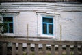 Facade of an old rural house with blue window frames. Old deformation of the wall structure caused by subsidence Royalty Free Stock Photo