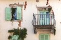 Facade of old shabby building with green shutters and balcony Royalty Free Stock Photo