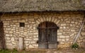 Facade of an old stone brick wall with wooden doors, a small window and thatched roof Royalty Free Stock Photo