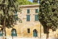 Facade of an old stone building with windows with green wooden shutters with a beautiful garden. Space for text Royalty Free Stock Photo