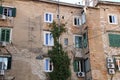 Facade of an old stylish tenement house, tenement house with green shutters, climbing plant on the wall of the old building, air c Royalty Free Stock Photo