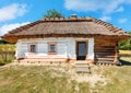 Facade of an old traditional Ukrainian rural house with a thatched roof on a summer day against a blue sky Royalty Free Stock Photo