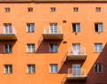 Facade of an orange building with its windows, balconys and shadows.