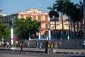 People walking in a central street in Old Havana with a tobacco factory in the background. Cuba