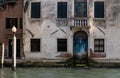 Facade of partially mossy old house with wooden blue vintage door on a canal in Venice, Italy Royalty Free Stock Photo