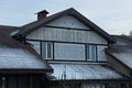 Facade of a private house with an attic of white wooden boards and windows under a brown slate roof Royalty Free Stock Photo